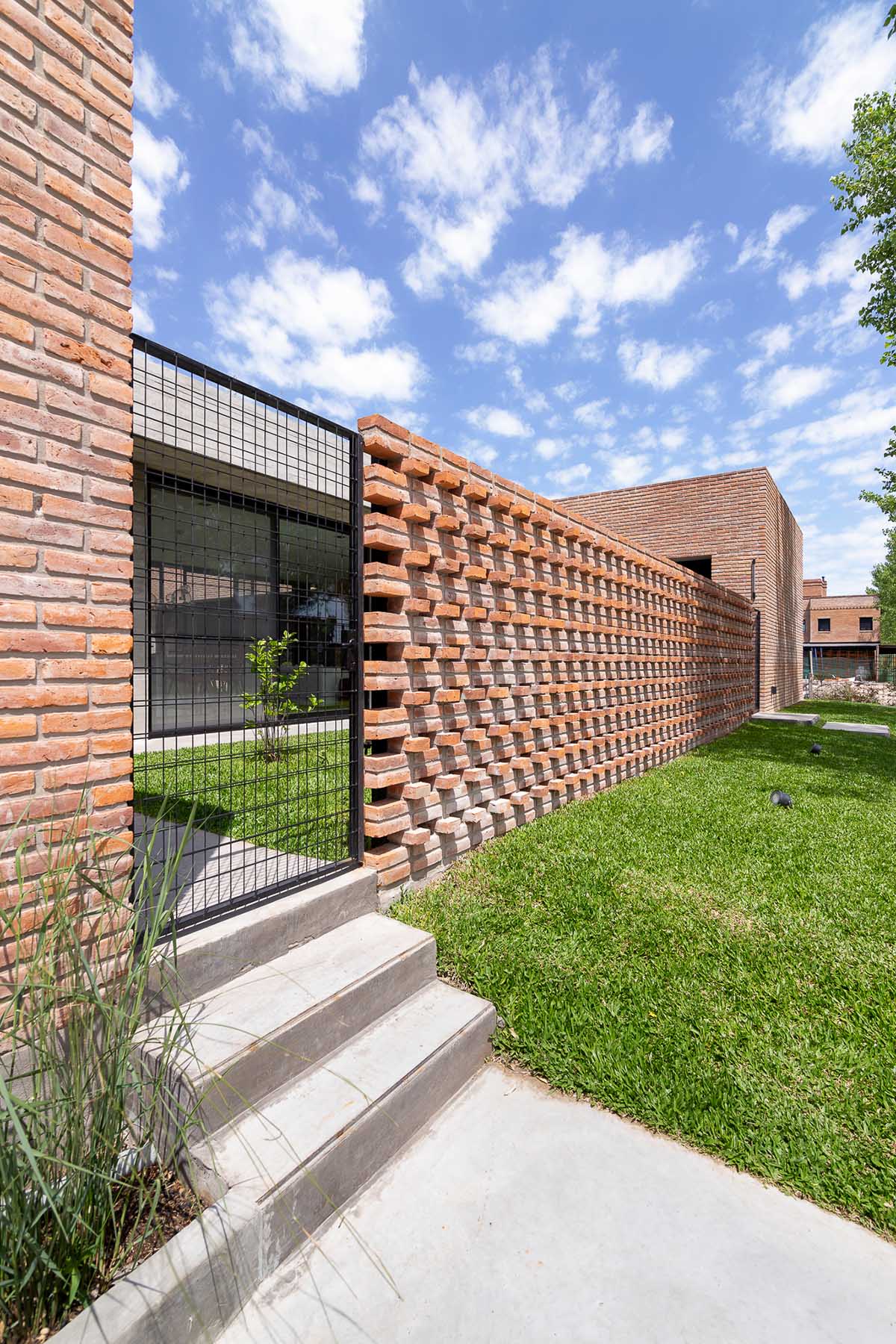 Nómade Arquitectura creates urban filter with large interlocked brick wall for house in Argentina