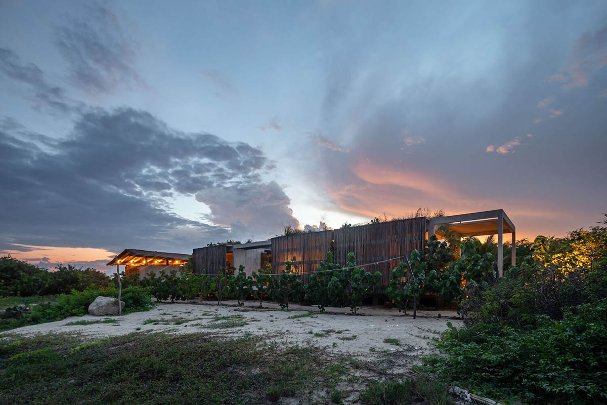 Concrete volumes are softened with wooden pergolas filtering light and patio in Casa Malandra