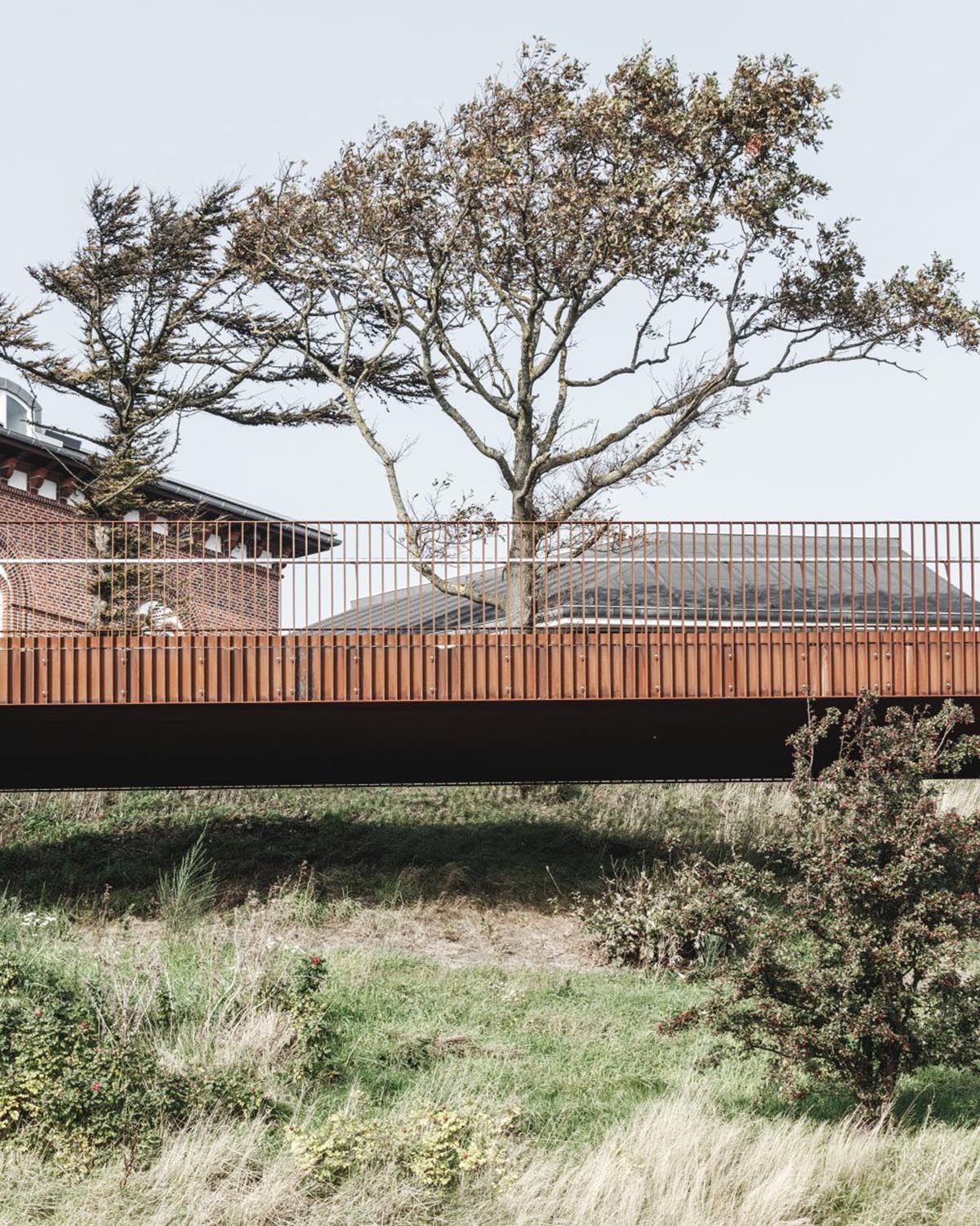 COBE's new pedestrian bridge raised on slim columns in industrial harbour area of Denmark