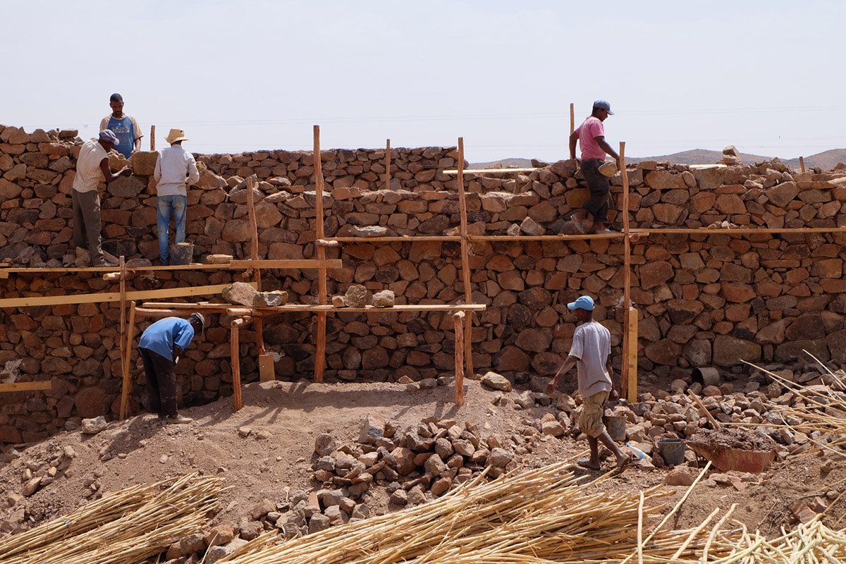 Two elongated walls made of granite rocks and earth form this women's house in a village of Morocco