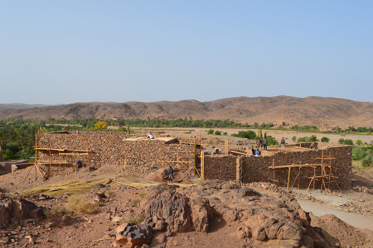 Two elongated walls made of granite rocks and earth form this women's house in a village of Morocco