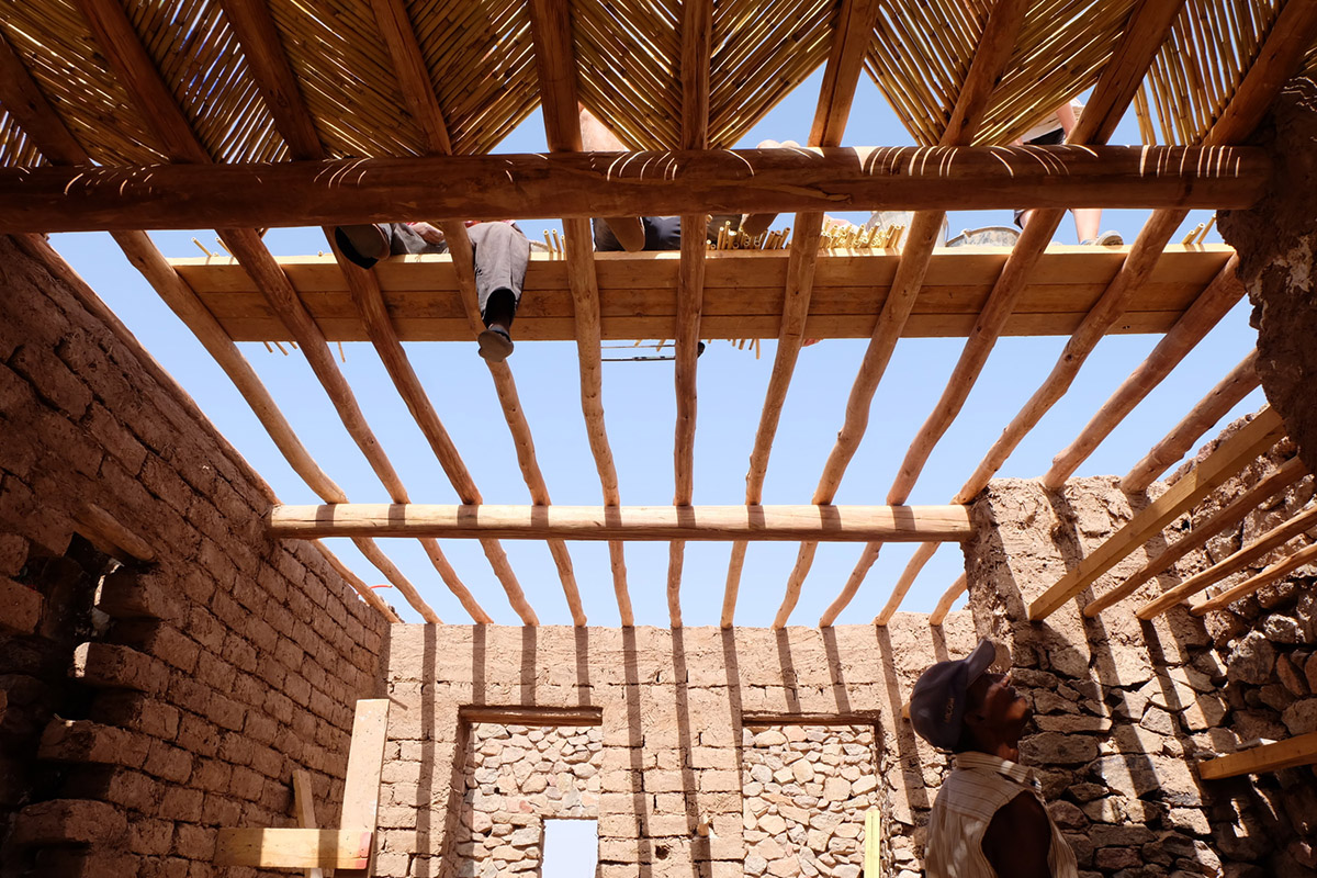 Two elongated walls made of granite rocks and earth form this women's house in a village of Morocco