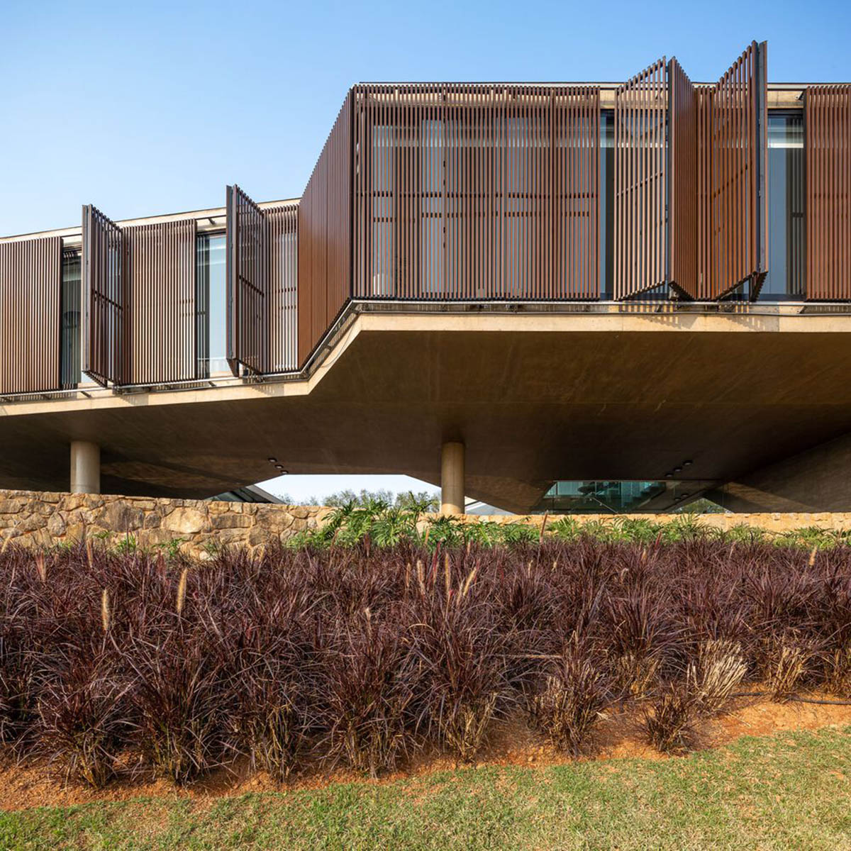 Bridge-like Brazilian house by Yuri Vital is supported by angular structural walls on sloped terrain