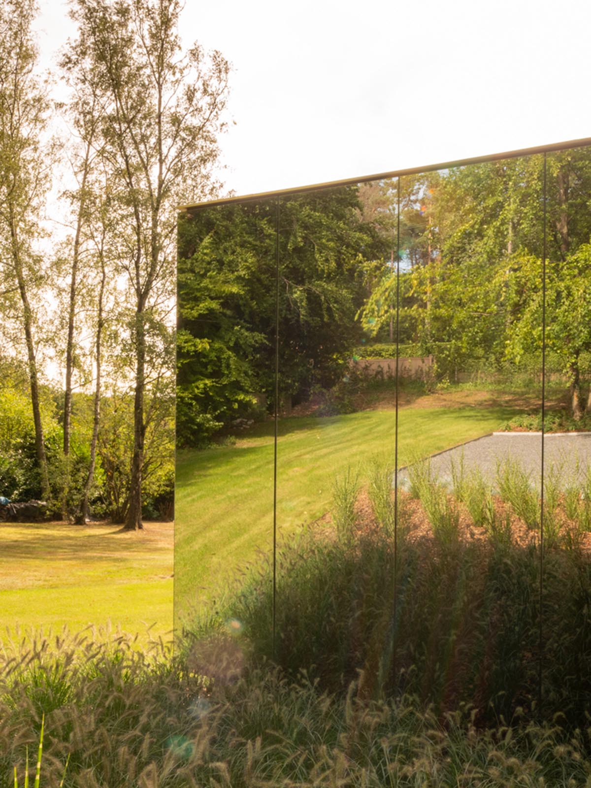 Office by MIA architecture is clad by mirrored panels to disappear in a lush environment in Belgium