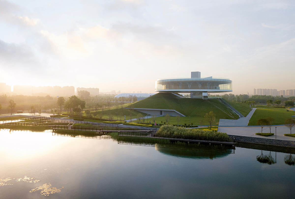 STUDIO A+ designs climbable ring-shaped art center on a green mound in ...