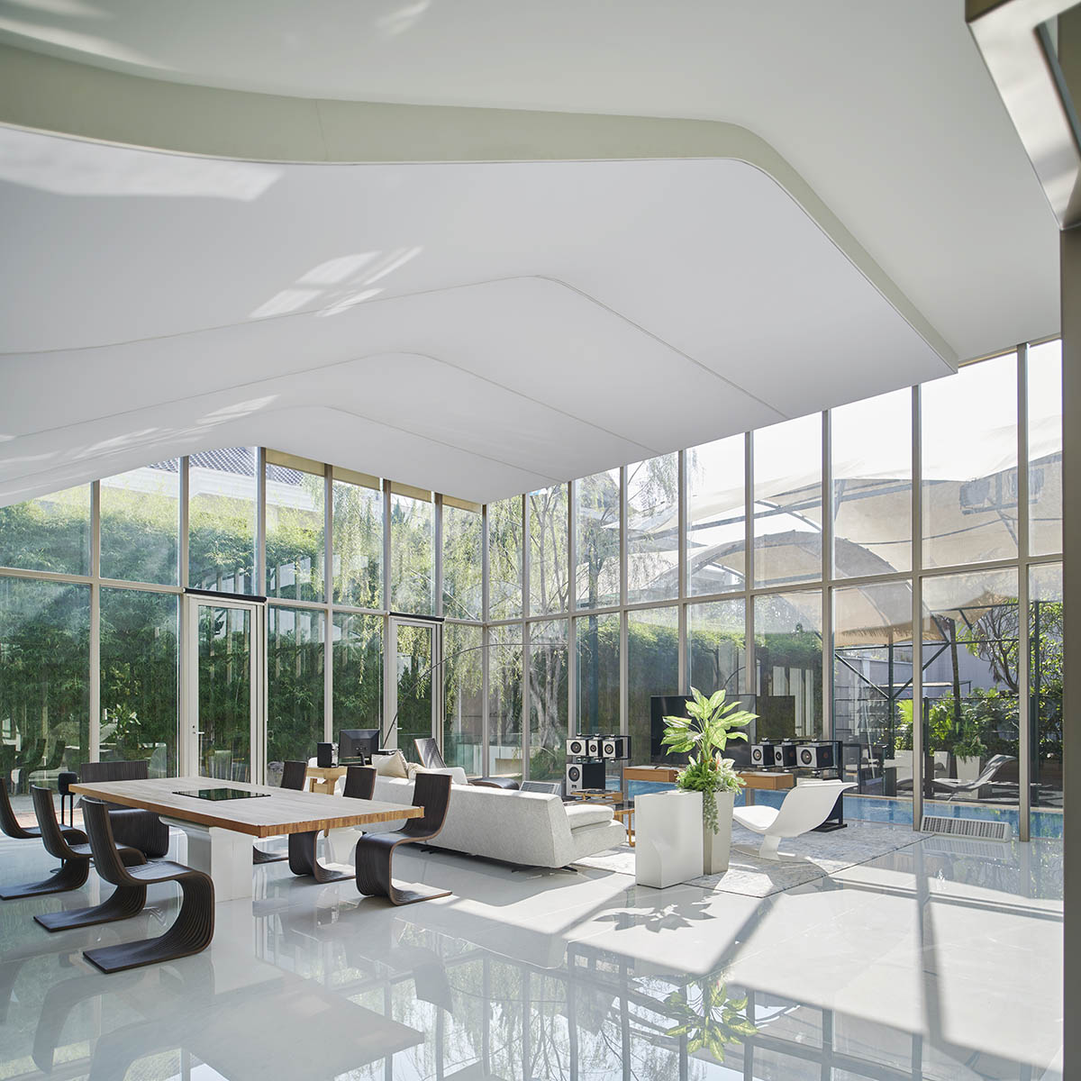 Undulating residence by RDMA is placed onto grass covered earth mound in Indonesia