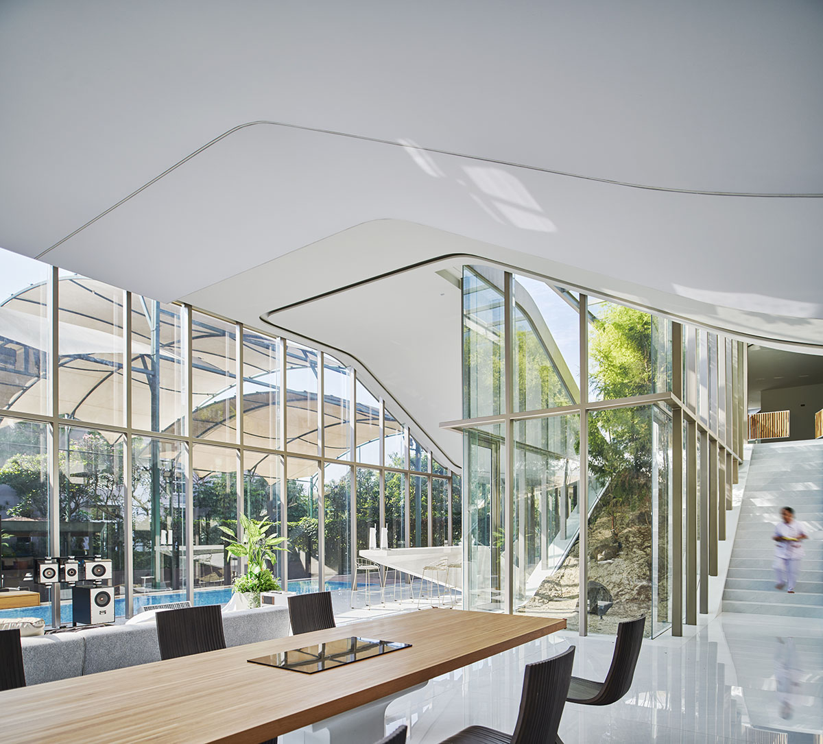 Undulating residence by RDMA is placed onto grass covered earth mound in Indonesia