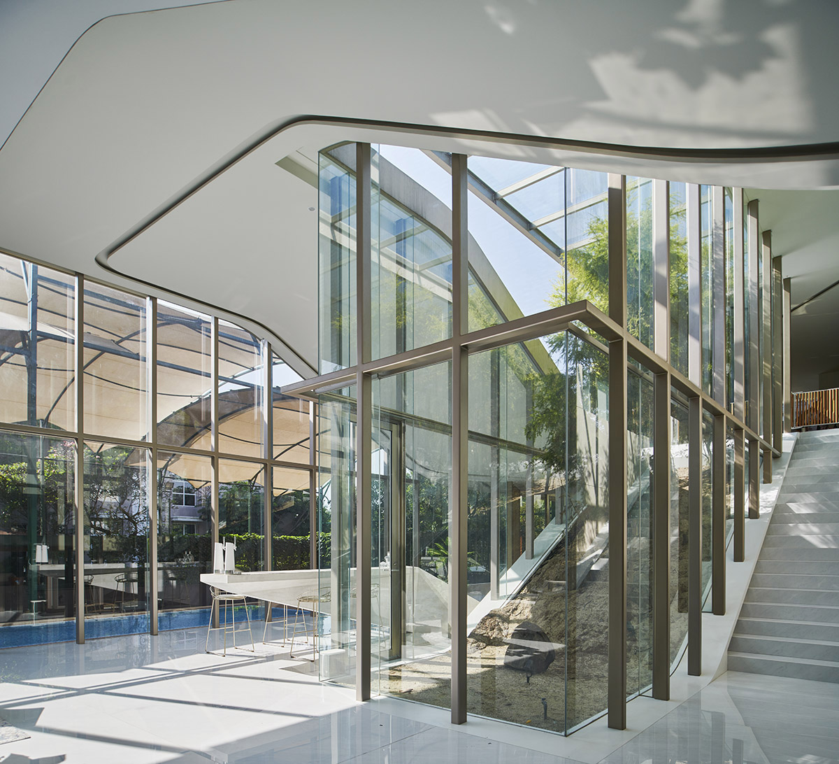 Undulating residence by RDMA is placed onto grass covered earth mound in Indonesia