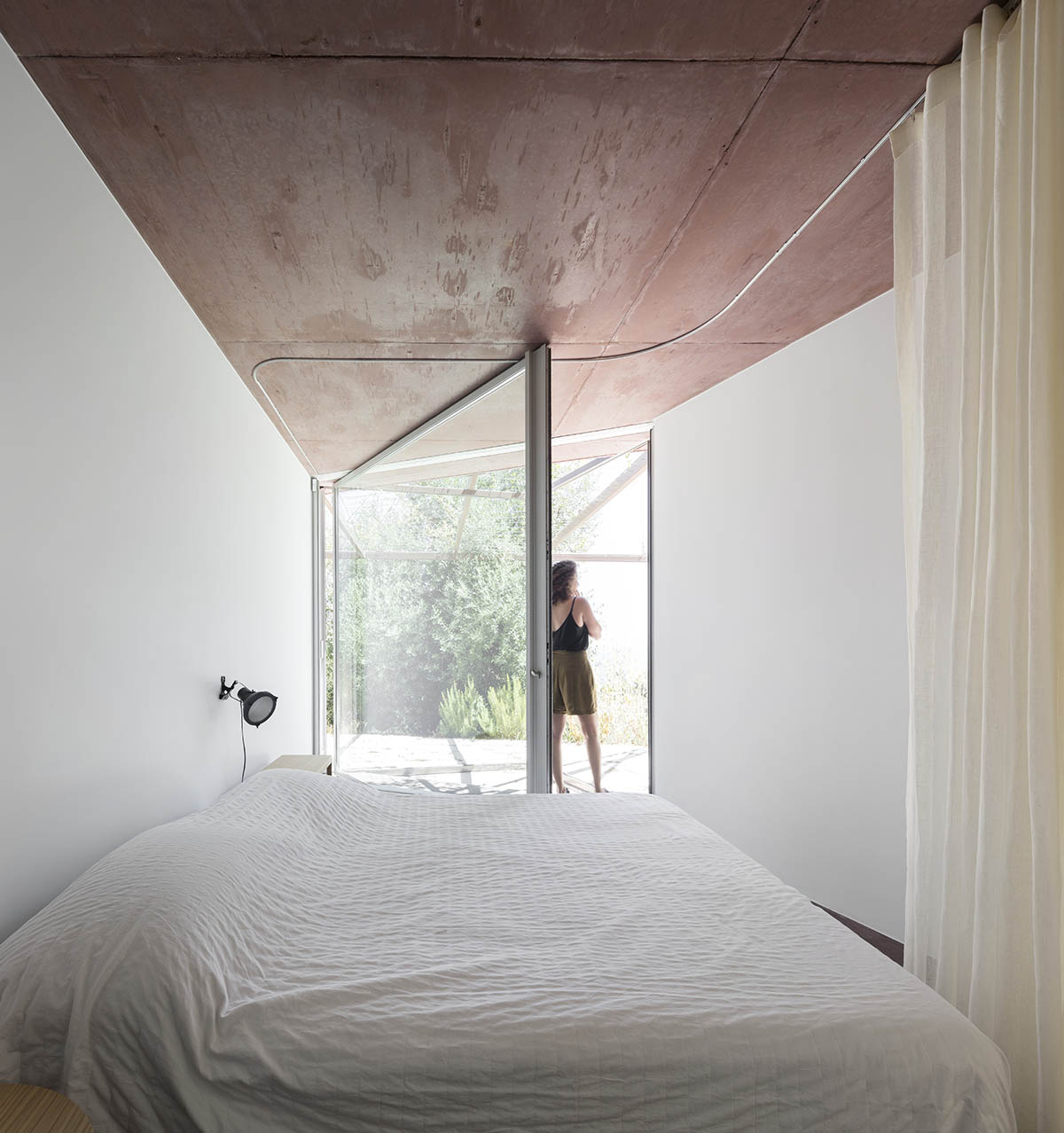 Earthy-toned twin houses by Extrastudio appear to emerge from the ground on a steep slope in Sesimbra