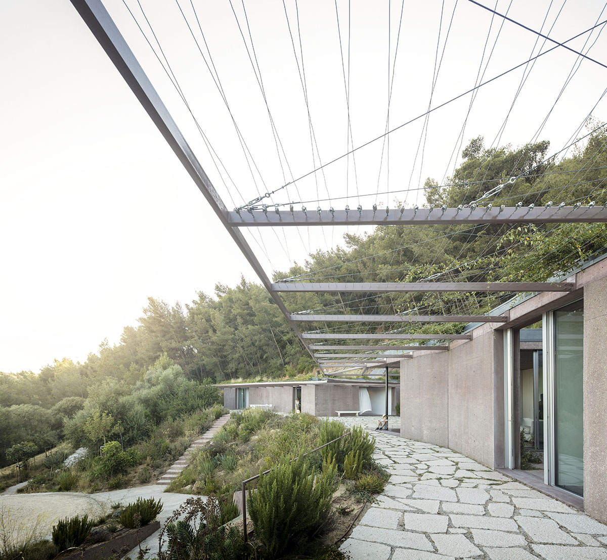 Earthy-toned twin houses by Extrastudio appear to emerge from the ground on a steep slope in Sesimbra