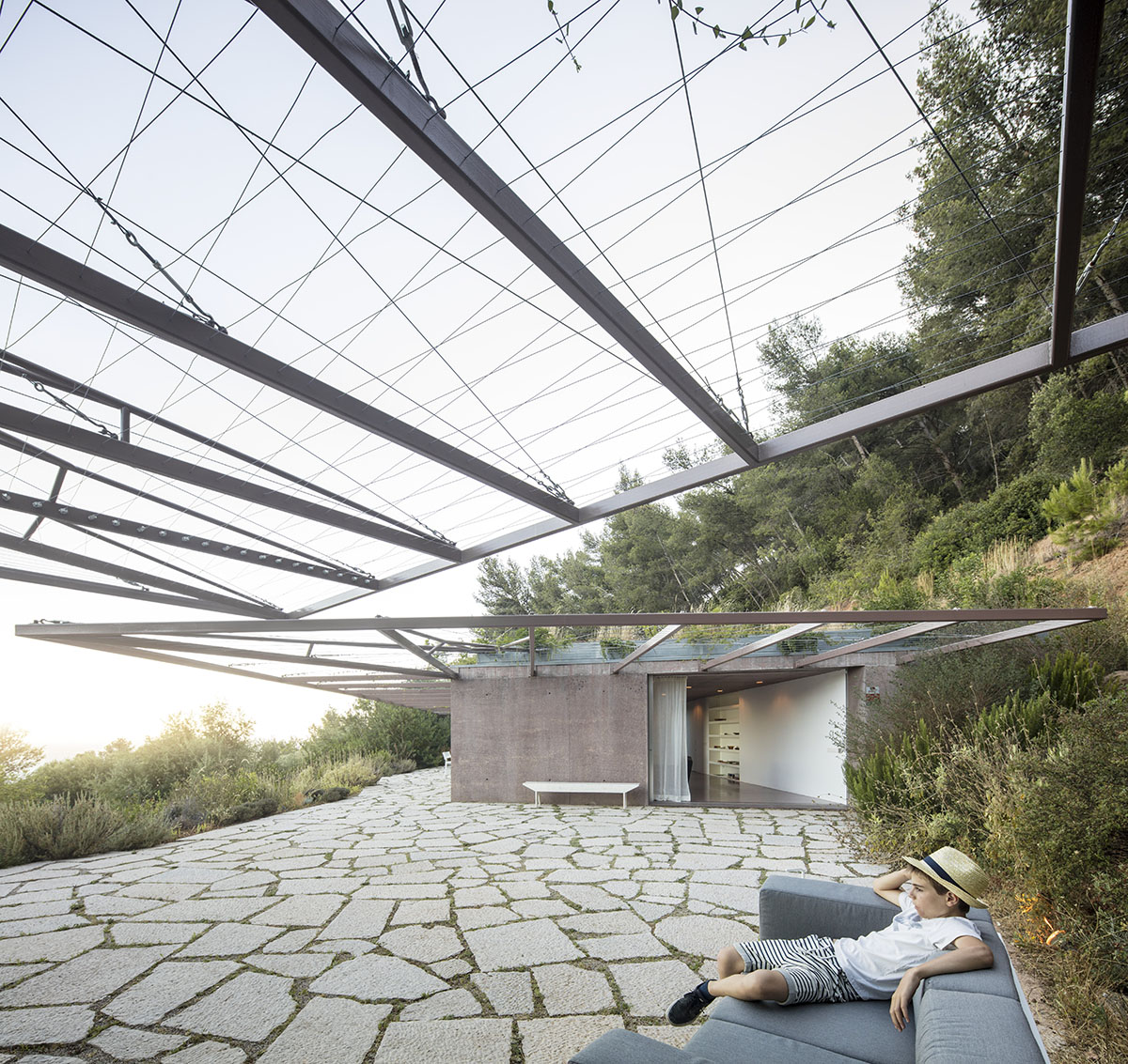 Earthy-toned twin houses by Extrastudio appear to emerge from the ground on a steep slope in Sesimbra