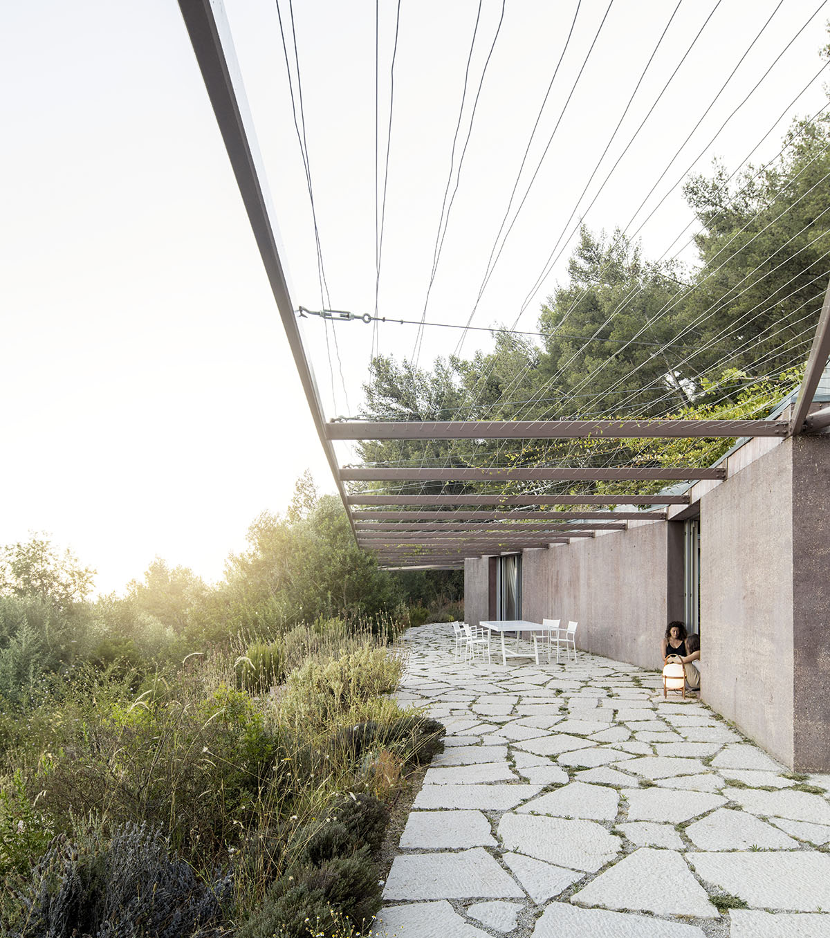 Earthy-toned twin houses by Extrastudio appear to emerge from the ground on a steep slope in Sesimbra