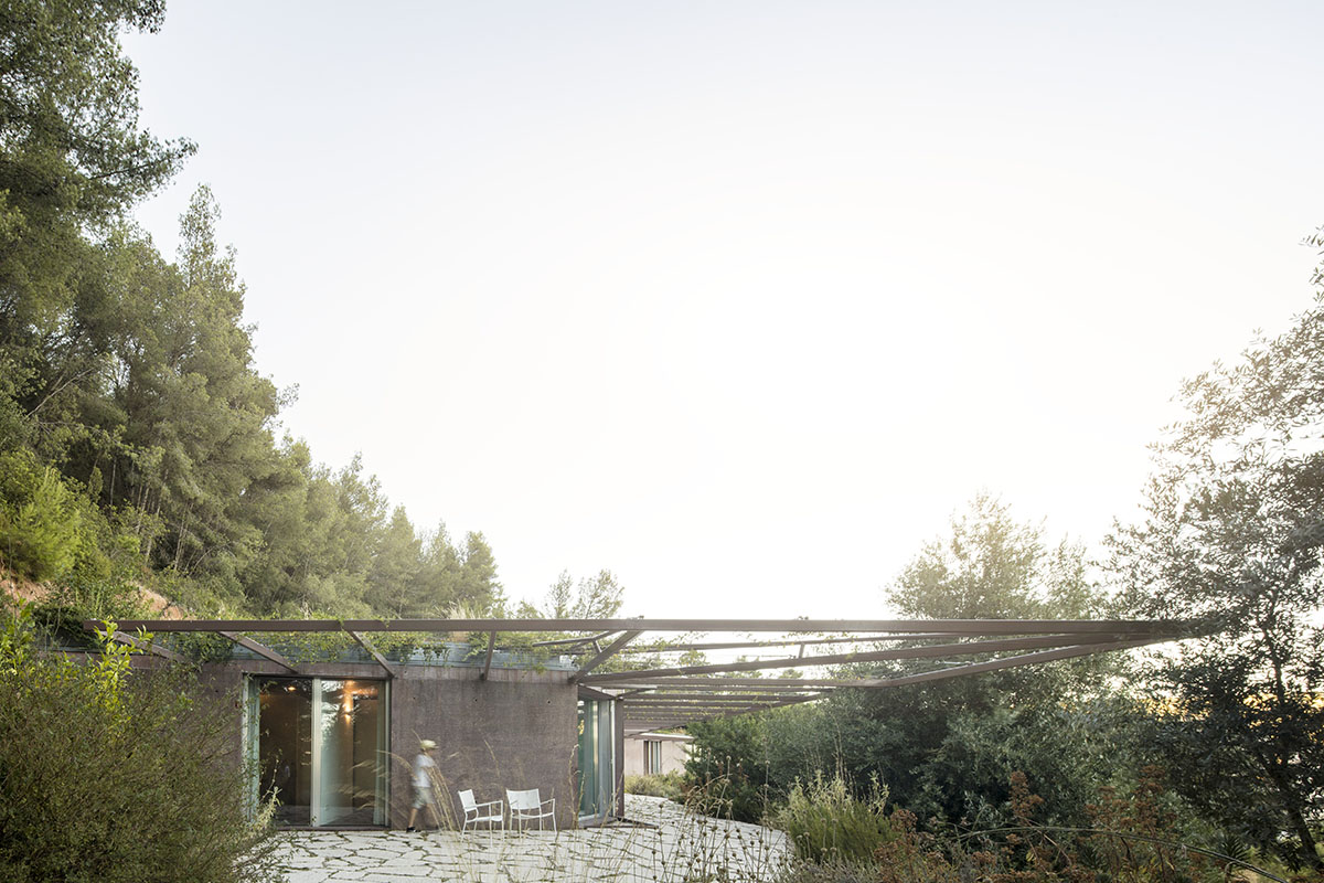 Earthy-toned twin houses by Extrastudio appear to emerge from the ground on a steep slope in Sesimbra