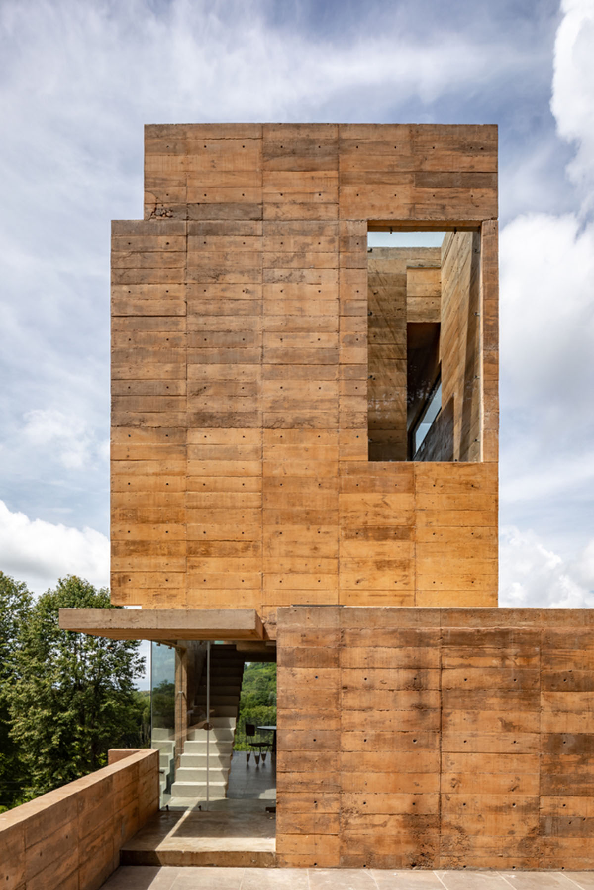 Earth-toned apartment building prioritizes views towards a forest in Coatepec, Mexico