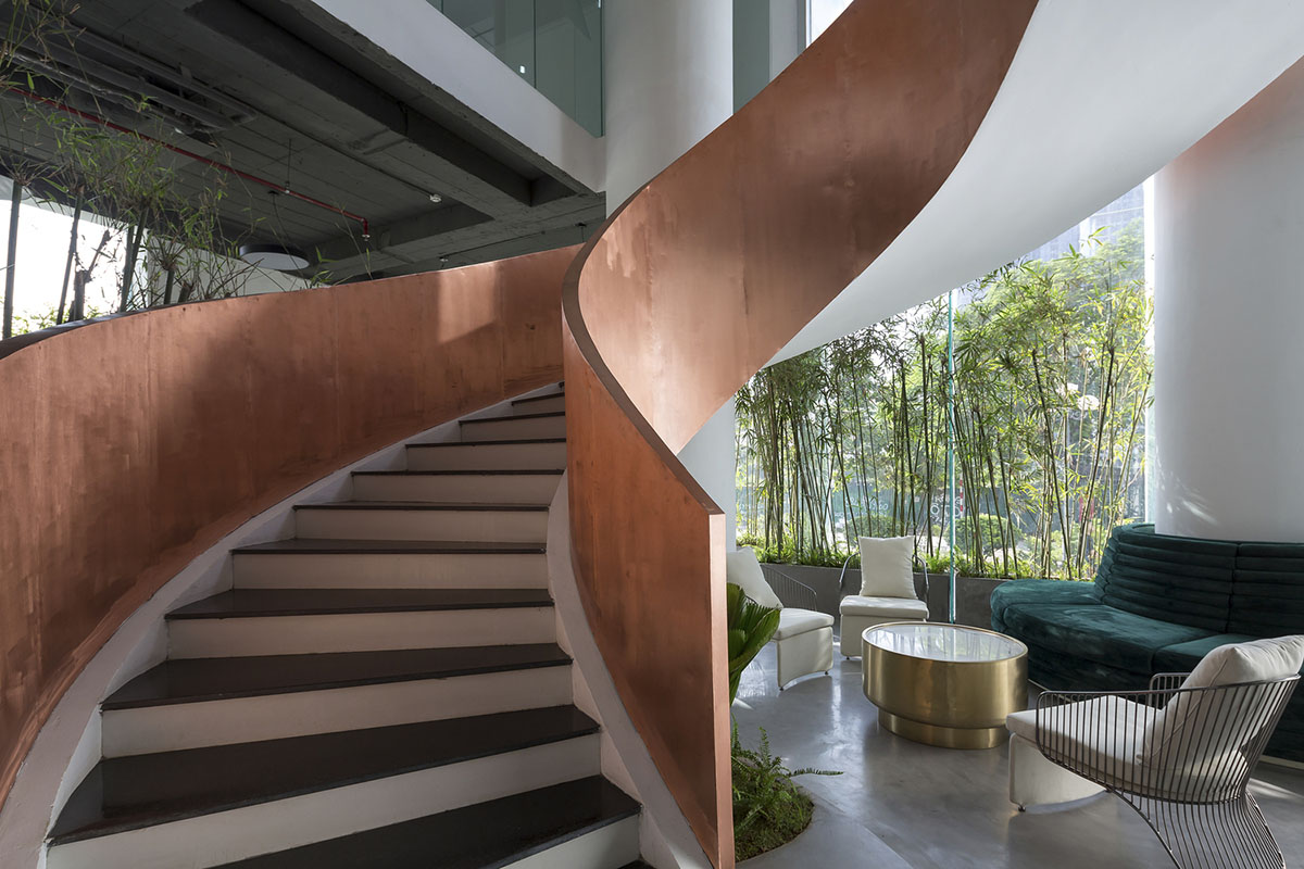 Copper-colored staircase and mini-bamboo trees provide tropical interior for this office in Vietnam