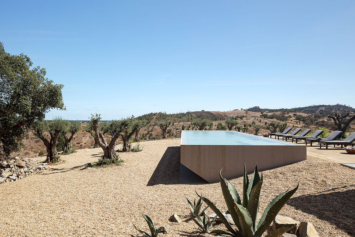 Low-profiled whitewashed stone walls wrap living units of Casa da Volta by PROMONTORIO and João Cravo