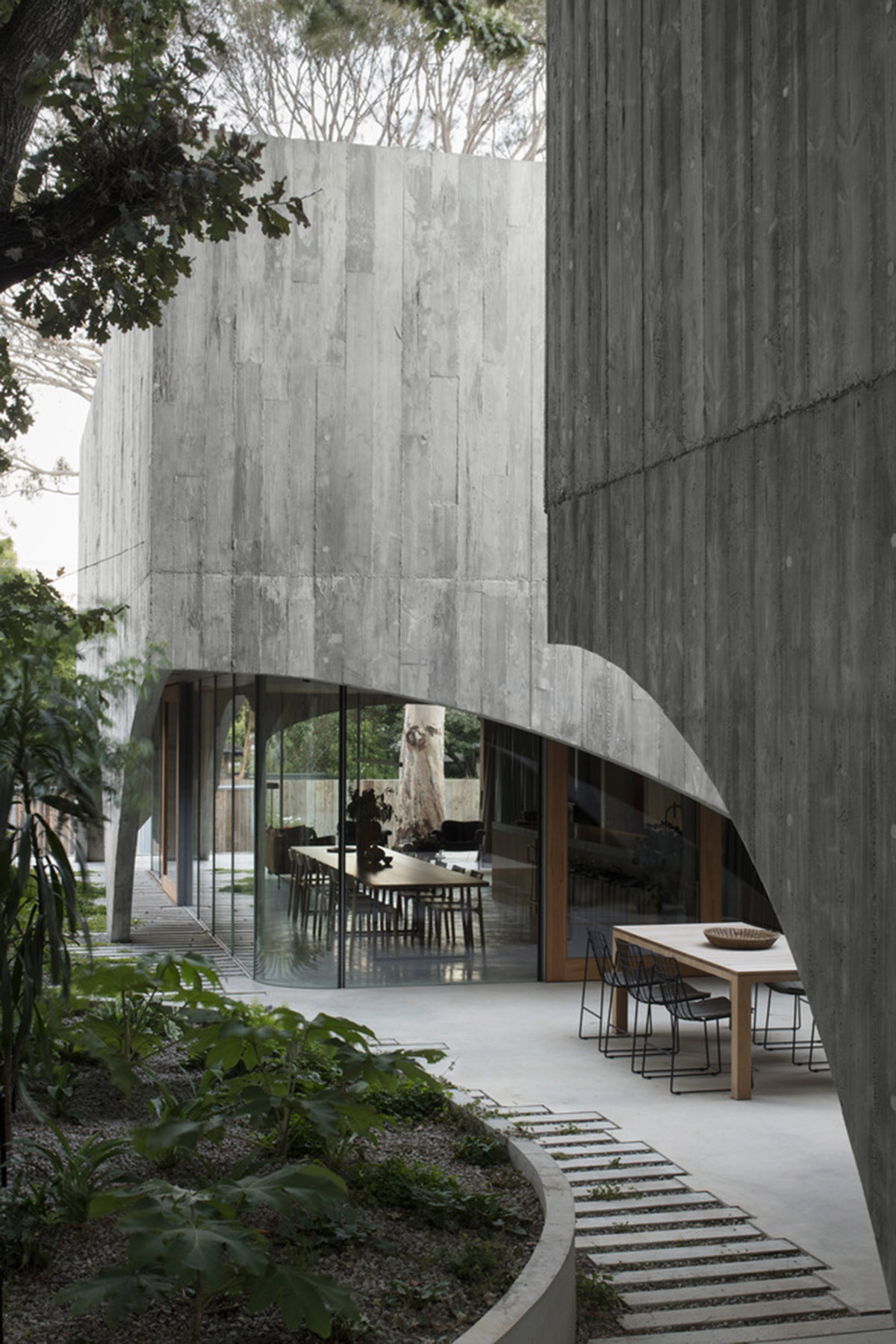 Arched concrete walls wrap a pair of houses as a secondary shelter in Australia