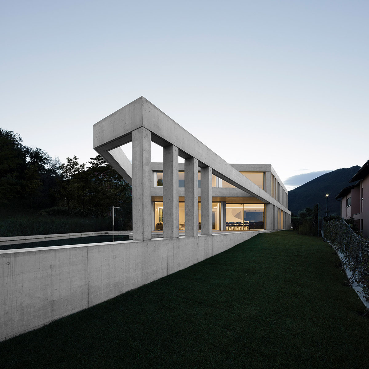 Grey concrete villa by DF_DC is characterised with trapezoidal colonnaded terrace on Comano hills