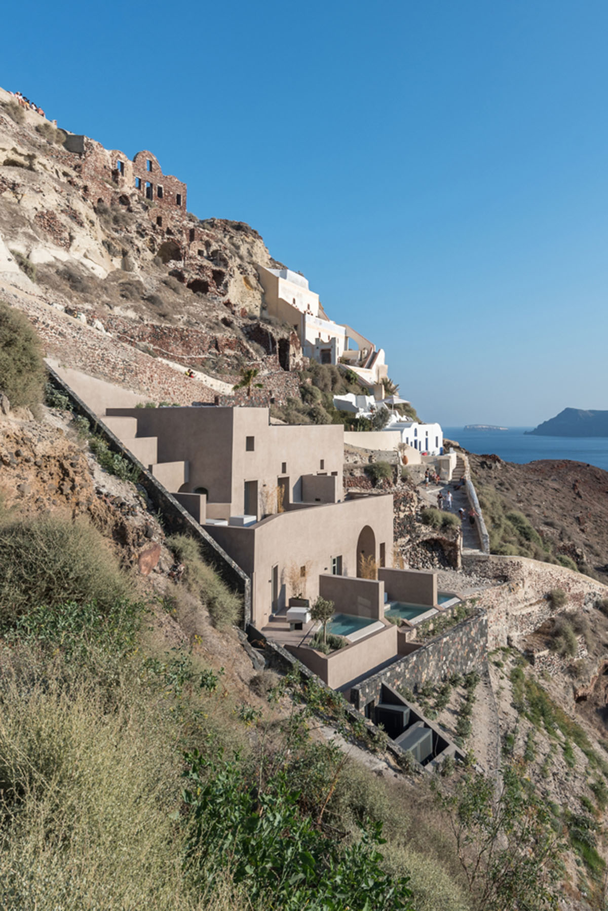 Kapsimalis Architects built castle-like hotel almost disappearing it on a steep hillside of Oia
