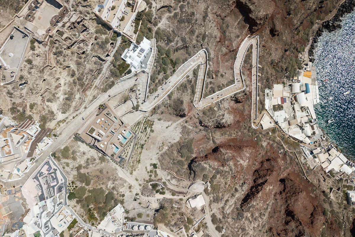 Kapsimalis Architects built castle-like hotel almost disappearing it on a steep hillside of Oia