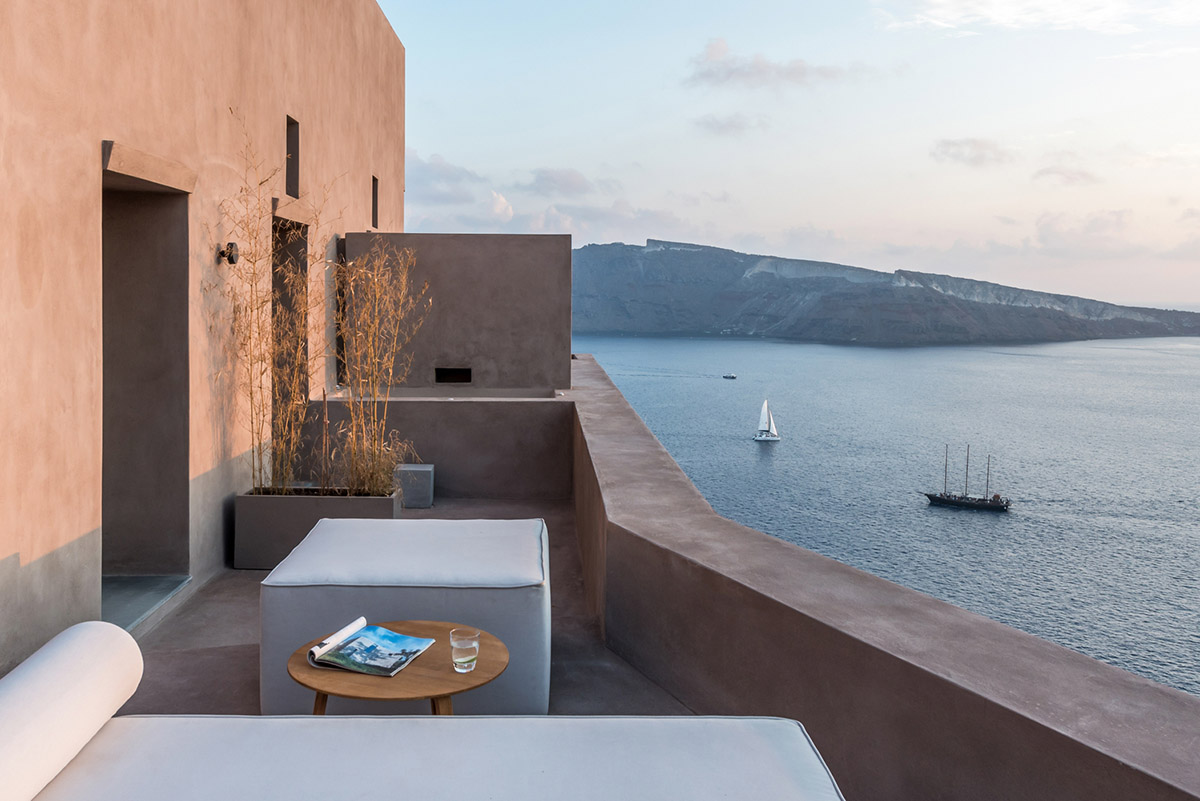 Kapsimalis Architects built castle-like hotel almost disappearing it on a steep hillside of Oia