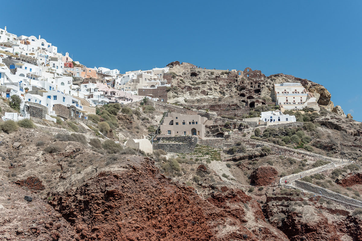 Kapsimalis Architects built castle-like hotel almost disappearing it on a steep hillside of Oia