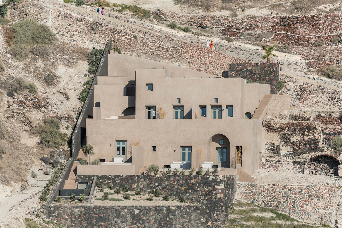 Kapsimalis Architects built castle-like hotel almost disappearing it on a steep hillside of Oia