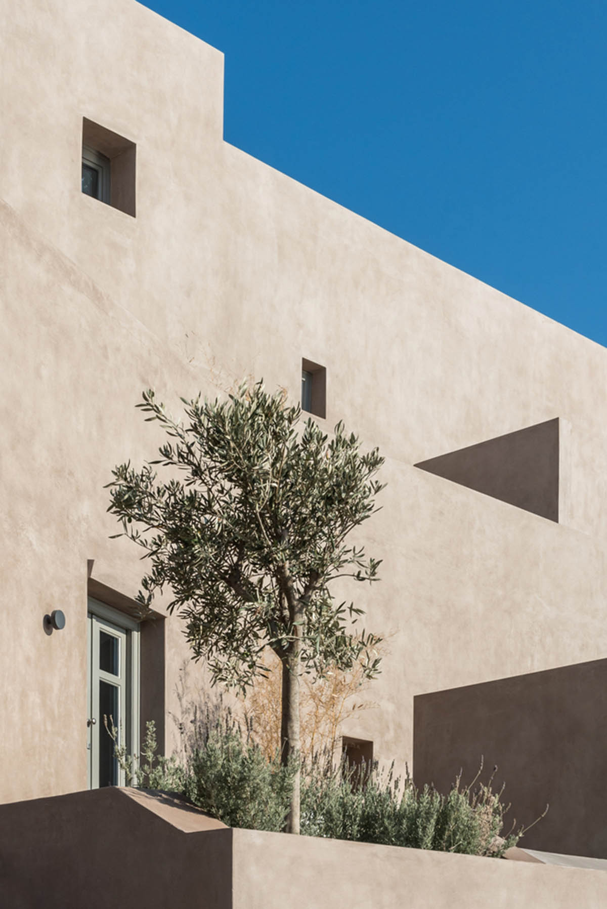 Kapsimalis Architects built castle-like hotel almost disappearing it on a steep hillside of Oia