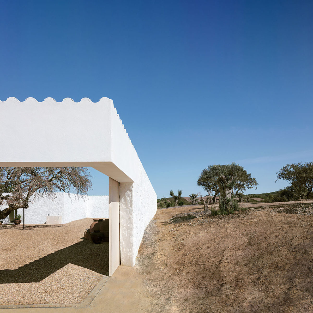 Low-profiled whitewashed stone walls wrap living units of Casa da Volta by PROMONTORIO and João Cravo