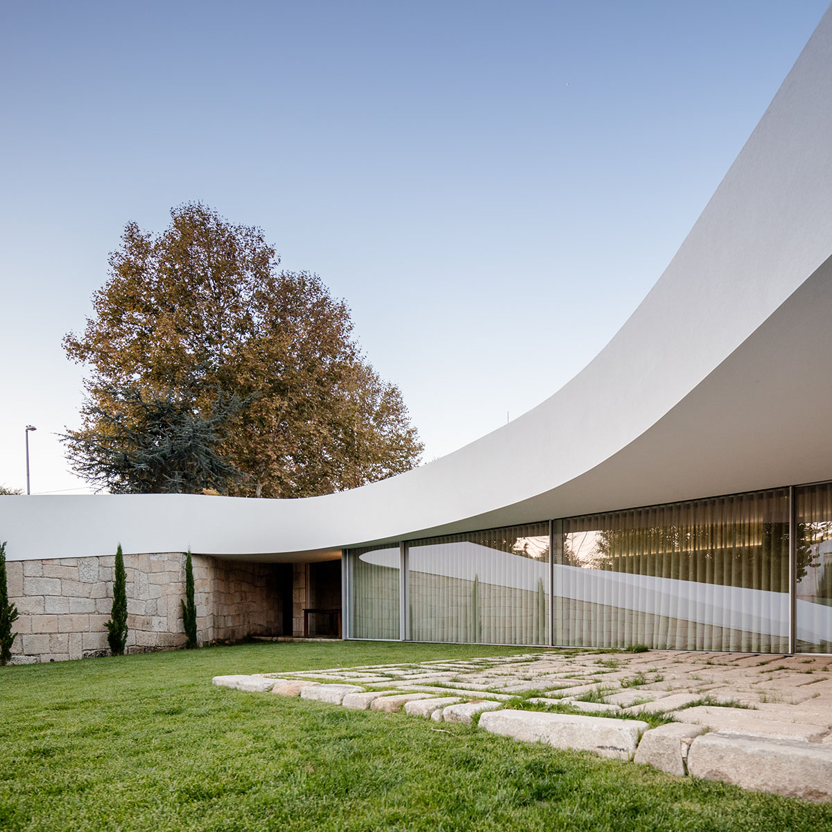 NOARQ designs smooth curvy-roof for Portuguese house to adapt to topography and create courtyards