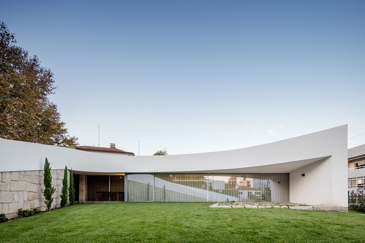 NOARQ designs smooth curvy-roof for Portuguese house to adapt to topography and create courtyards