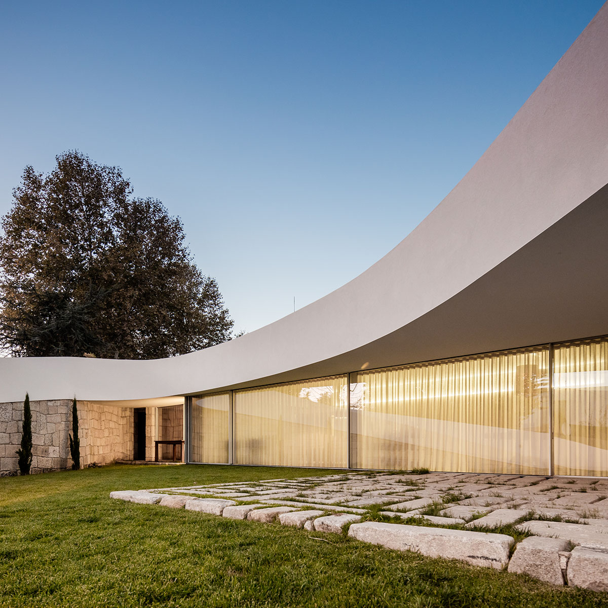 NOARQ designs smooth curvy-roof for Portuguese house to adapt to topography and create courtyards