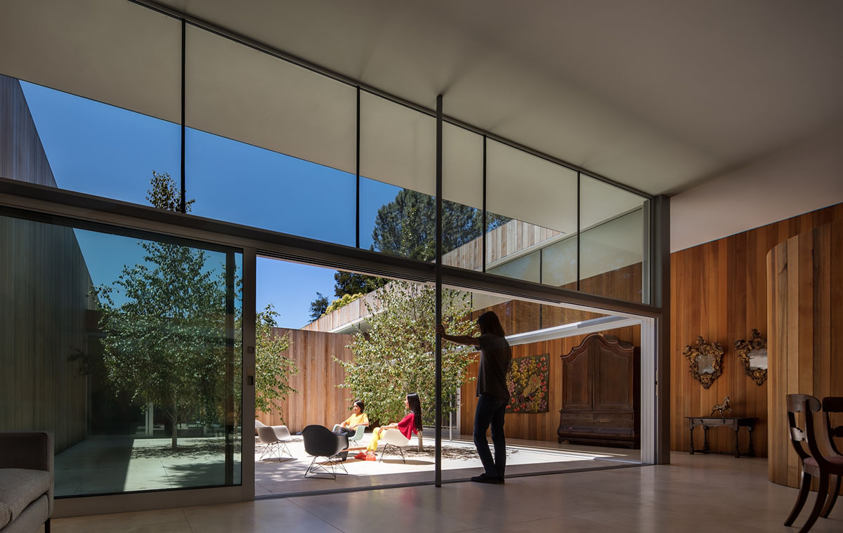 Curving wooden walls form Roofless House among trees in Atherton
