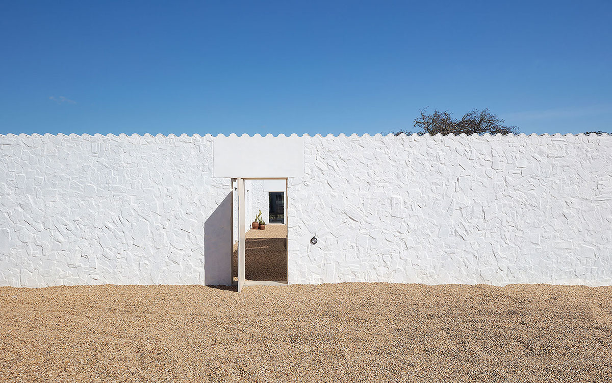Low-profiled whitewashed stone walls wrap living units of Casa da Volta by PROMONTORIO and João Cravo