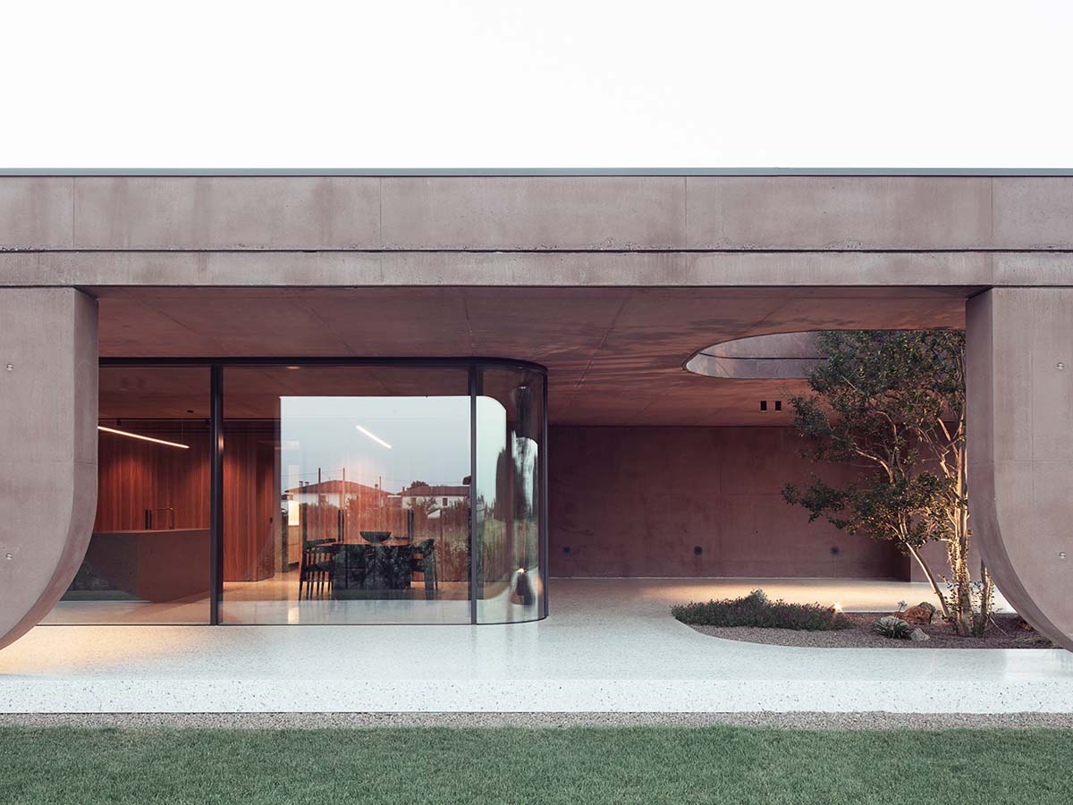 Red pigmented house by MIDE architetti features a large porch profiled by geometrical openings 