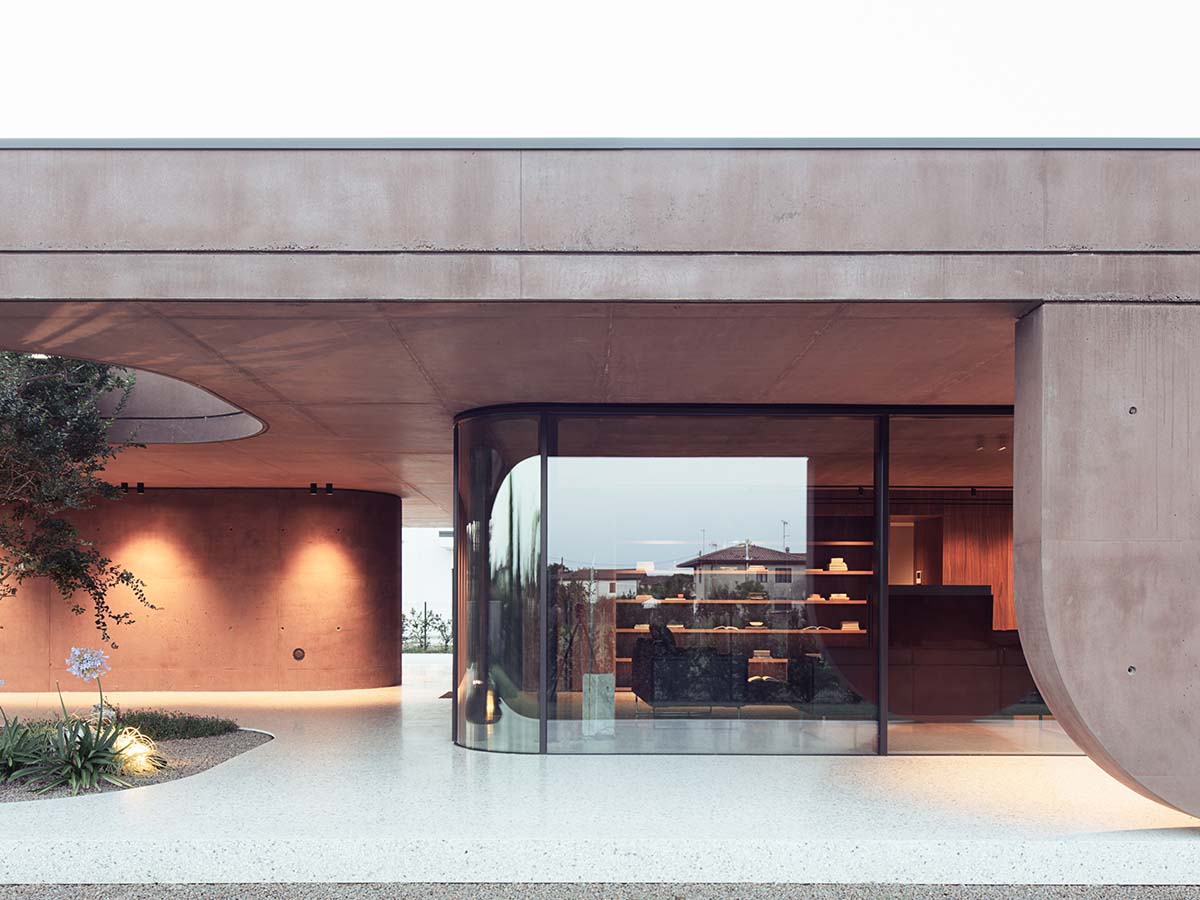 Red pigmented house by MIDE architetti features a large porch profiled by geometrical openings 