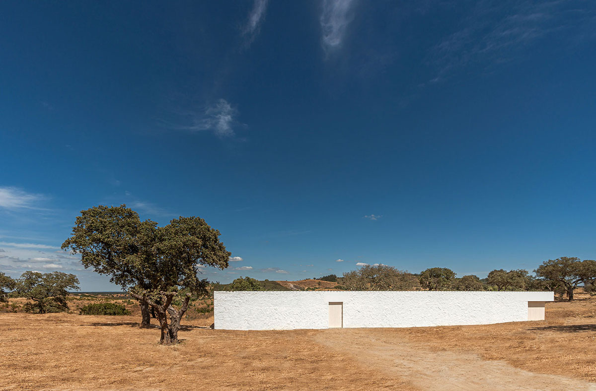 Low-profiled whitewashed stone walls wrap living units of Casa da Volta by PROMONTORIO and João Cravo