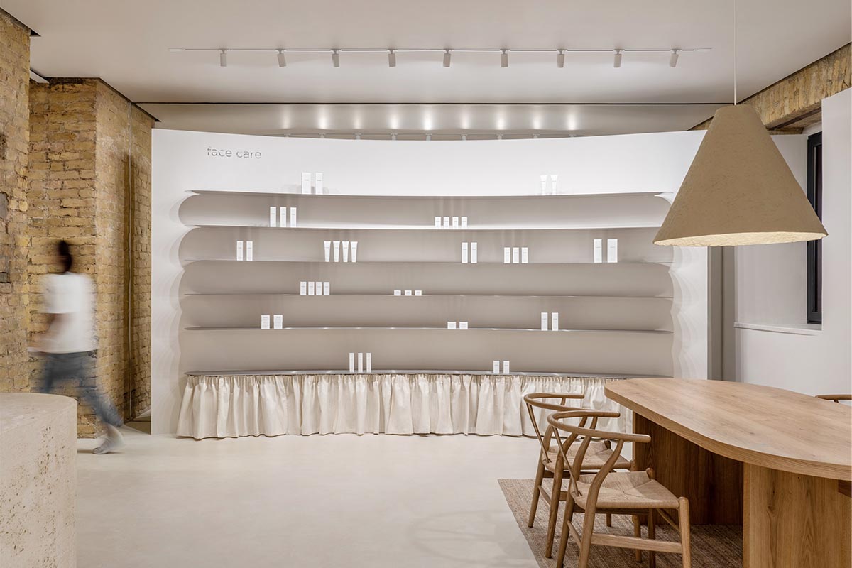 Tactile brick complements beige hues and mirrored surfaces for the interior of cosmetic showroom
