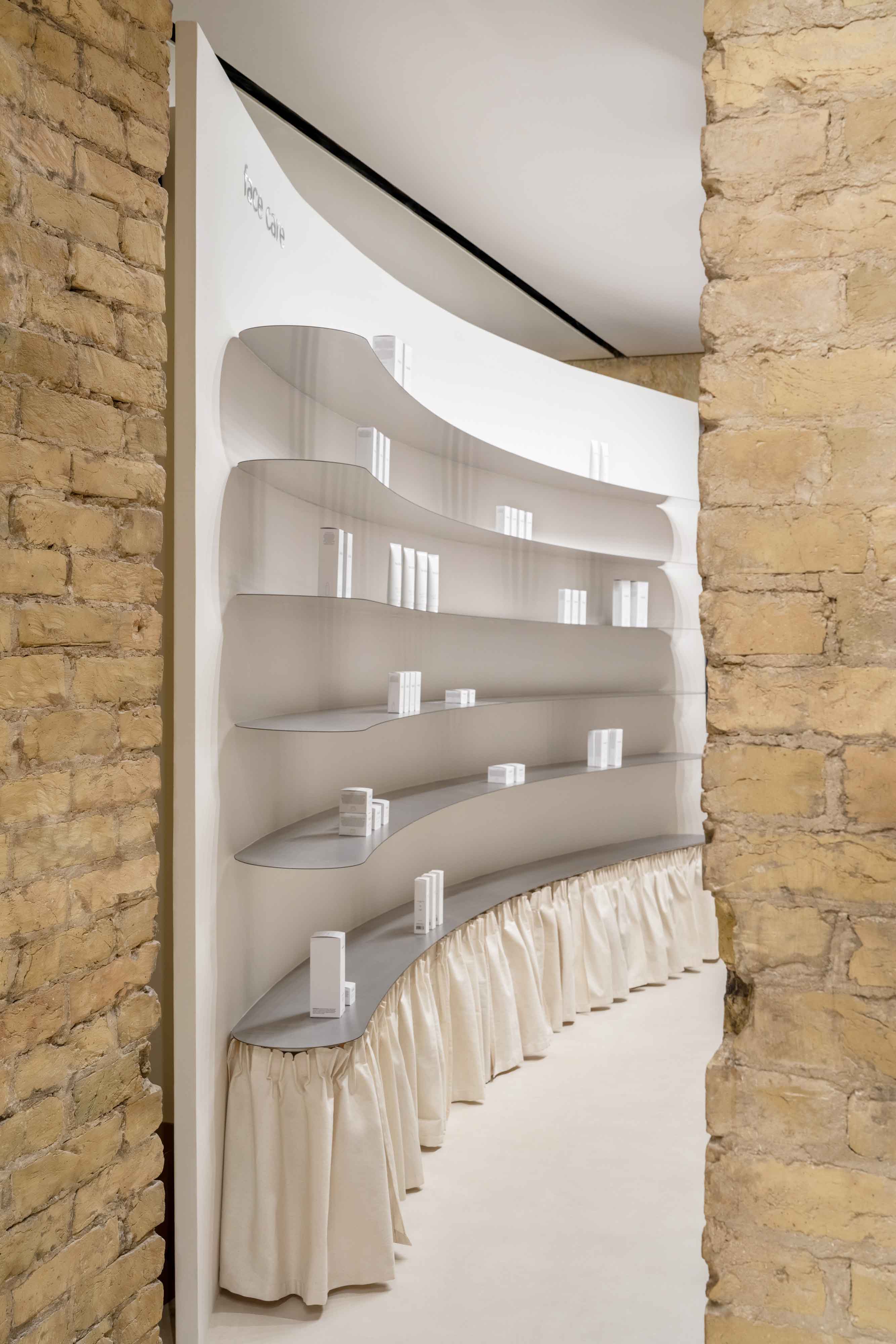 Tactile brick complements beige hues and mirrored surfaces for the interior of cosmetic showroom