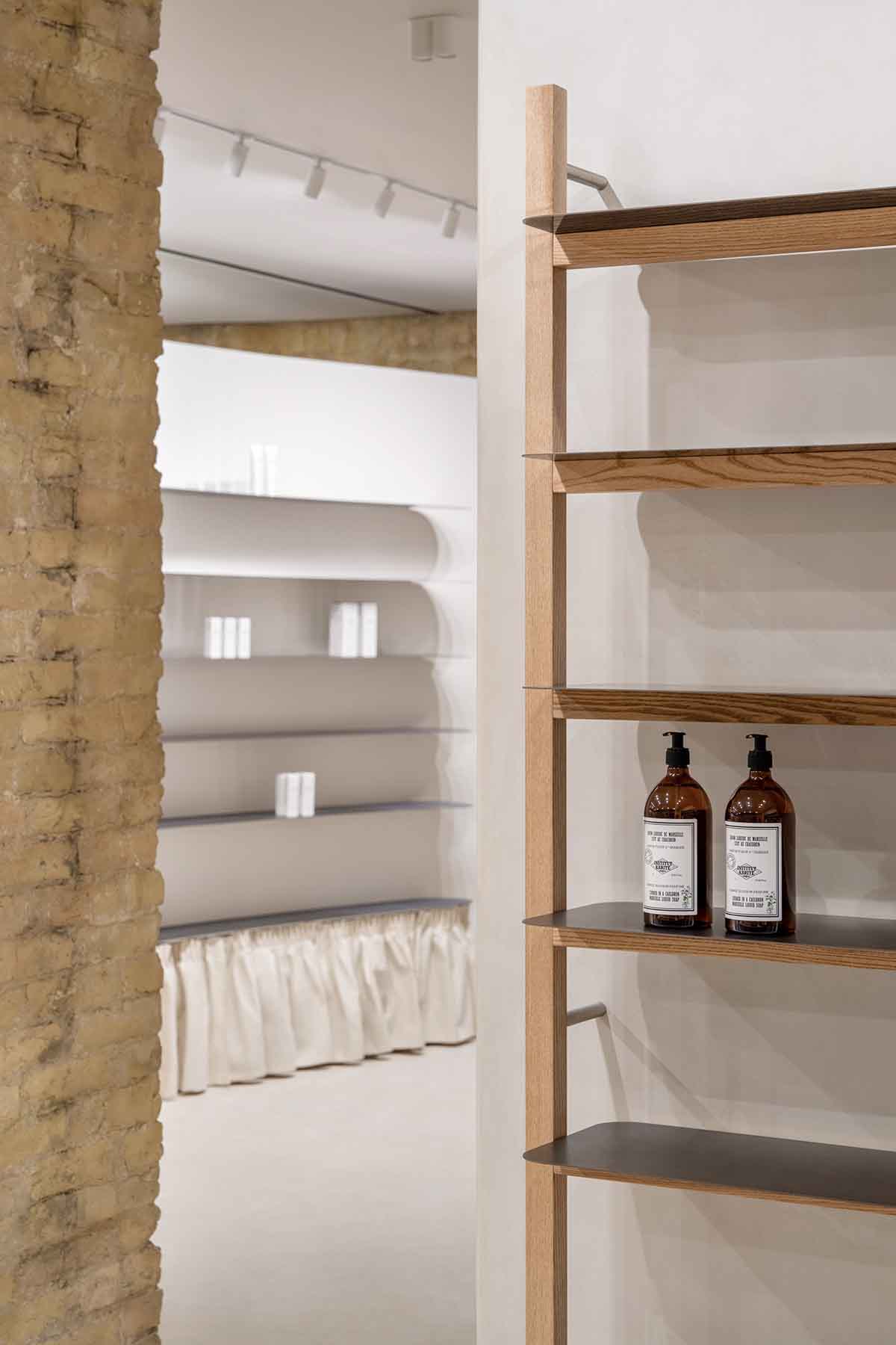 Tactile brick complements beige hues and mirrored surfaces for the interior of cosmetic showroom