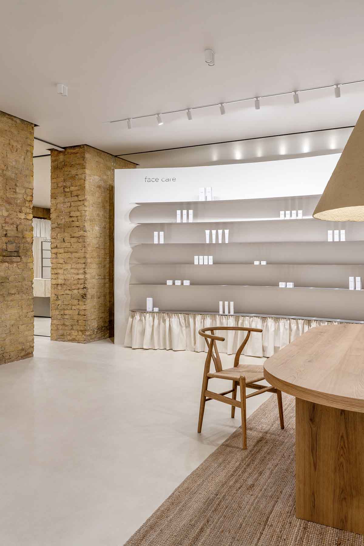 Tactile brick complements beige hues and mirrored surfaces for the interior of cosmetic showroom