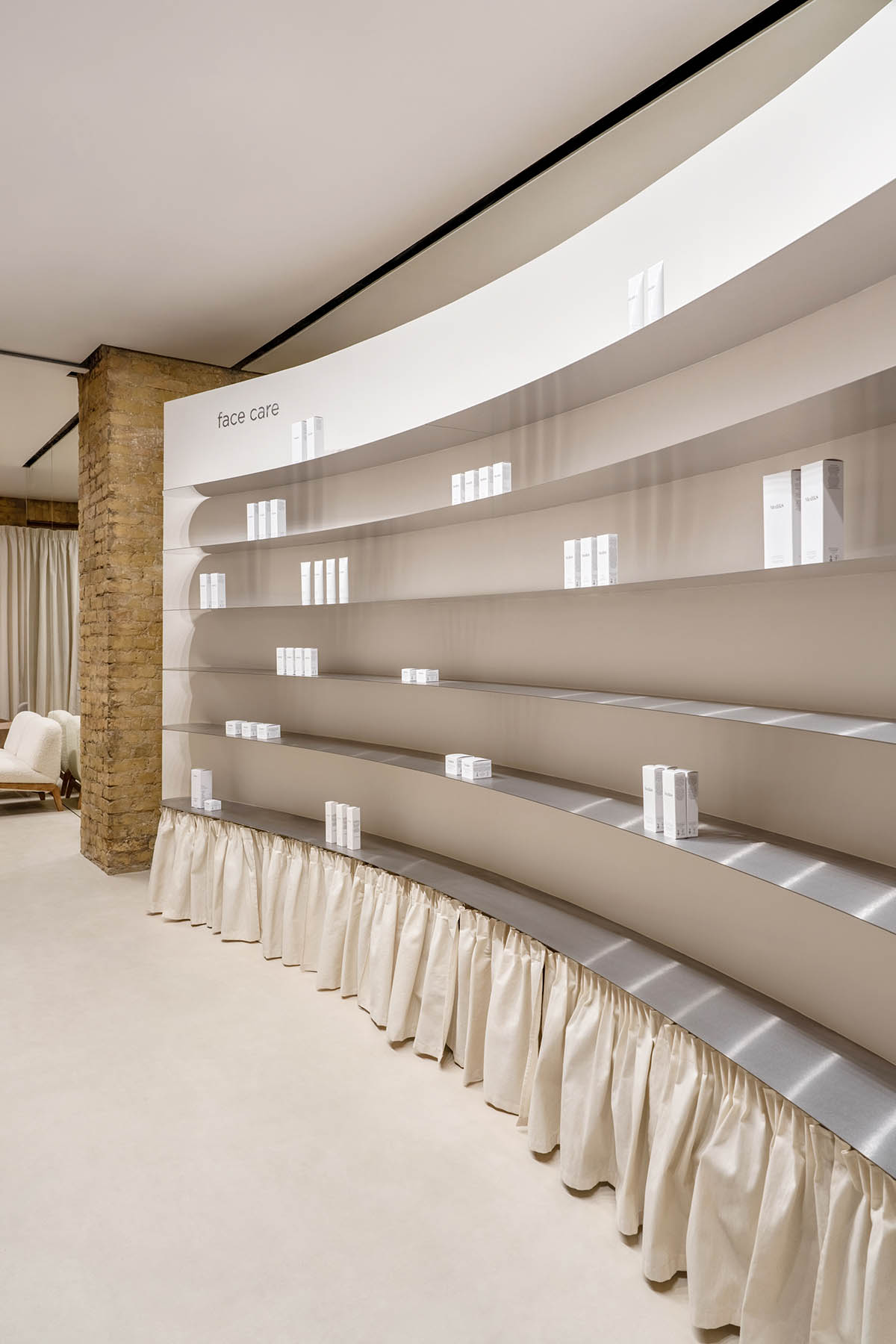 Tactile brick complements beige hues and mirrored surfaces for the interior of cosmetic showroom