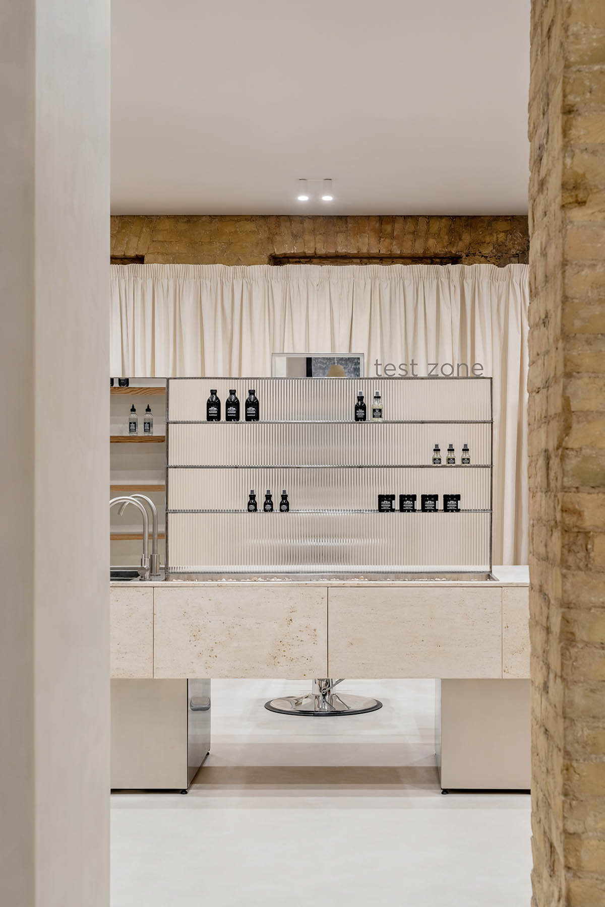 Tactile brick complements beige hues and mirrored surfaces for the interior of cosmetic showroom