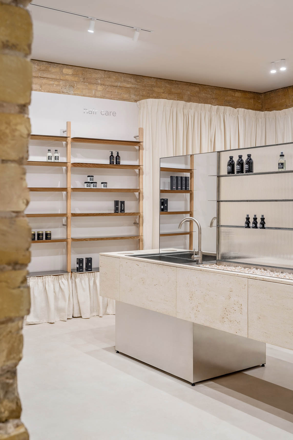 Tactile brick complements beige hues and mirrored surfaces for the interior of cosmetic showroom