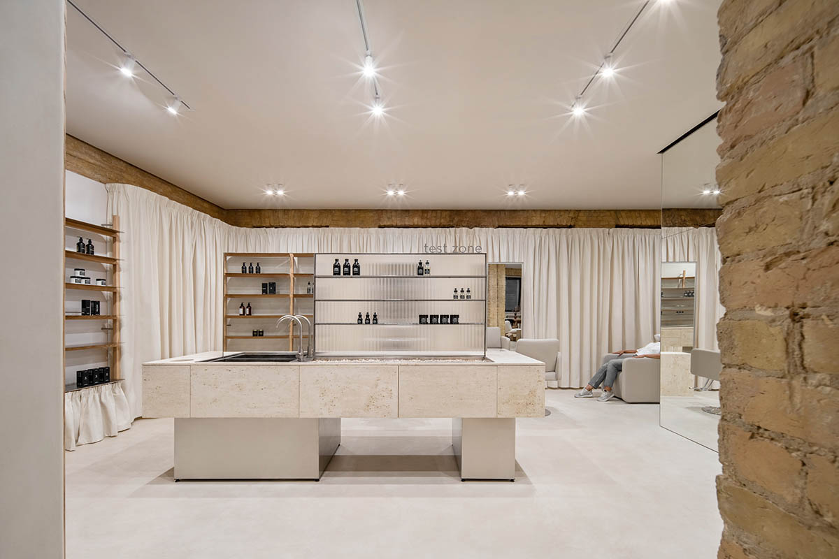 Tactile brick complements beige hues and mirrored surfaces for the interior of cosmetic showroom