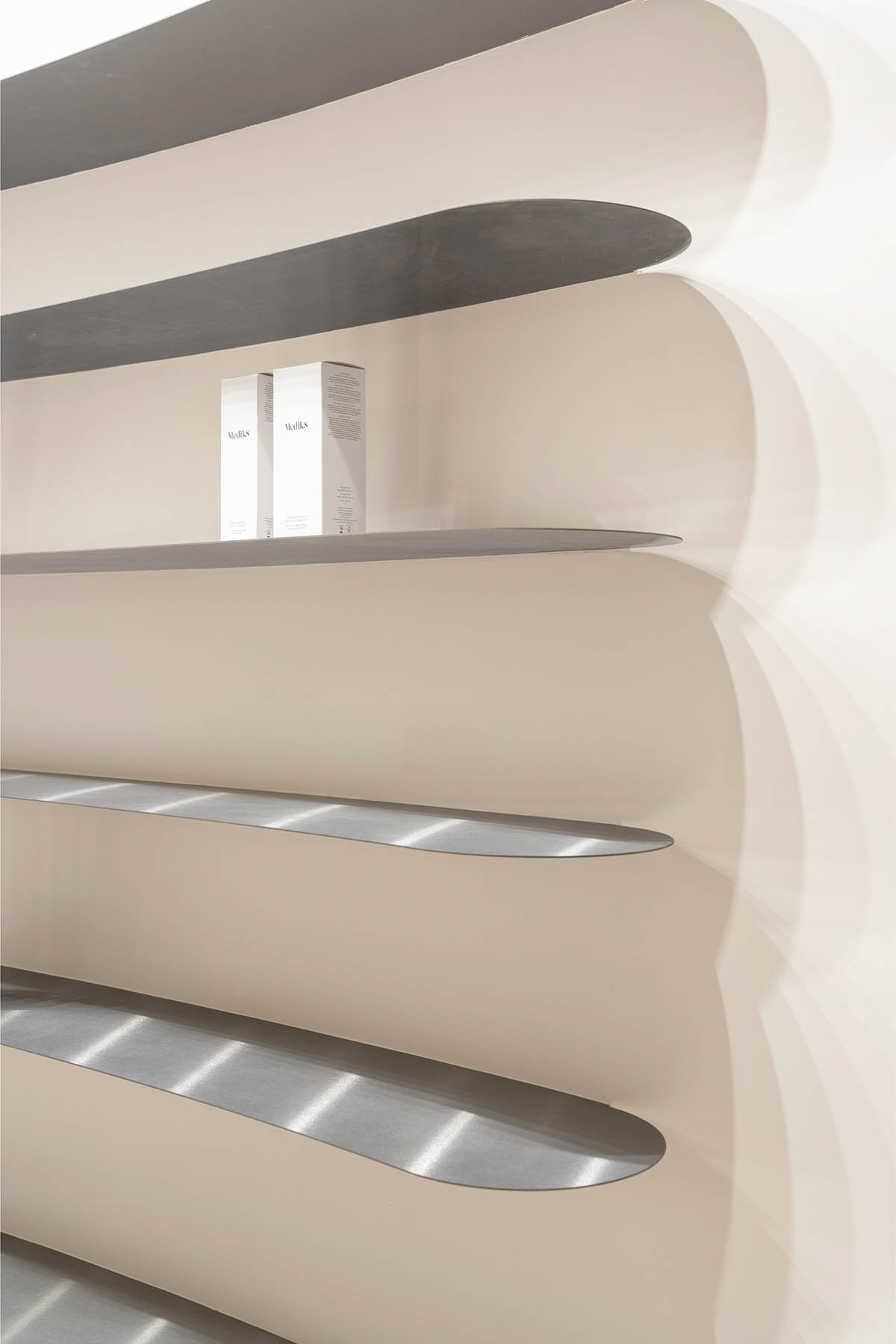 Tactile brick complements beige hues and mirrored surfaces for the interior of cosmetic showroom