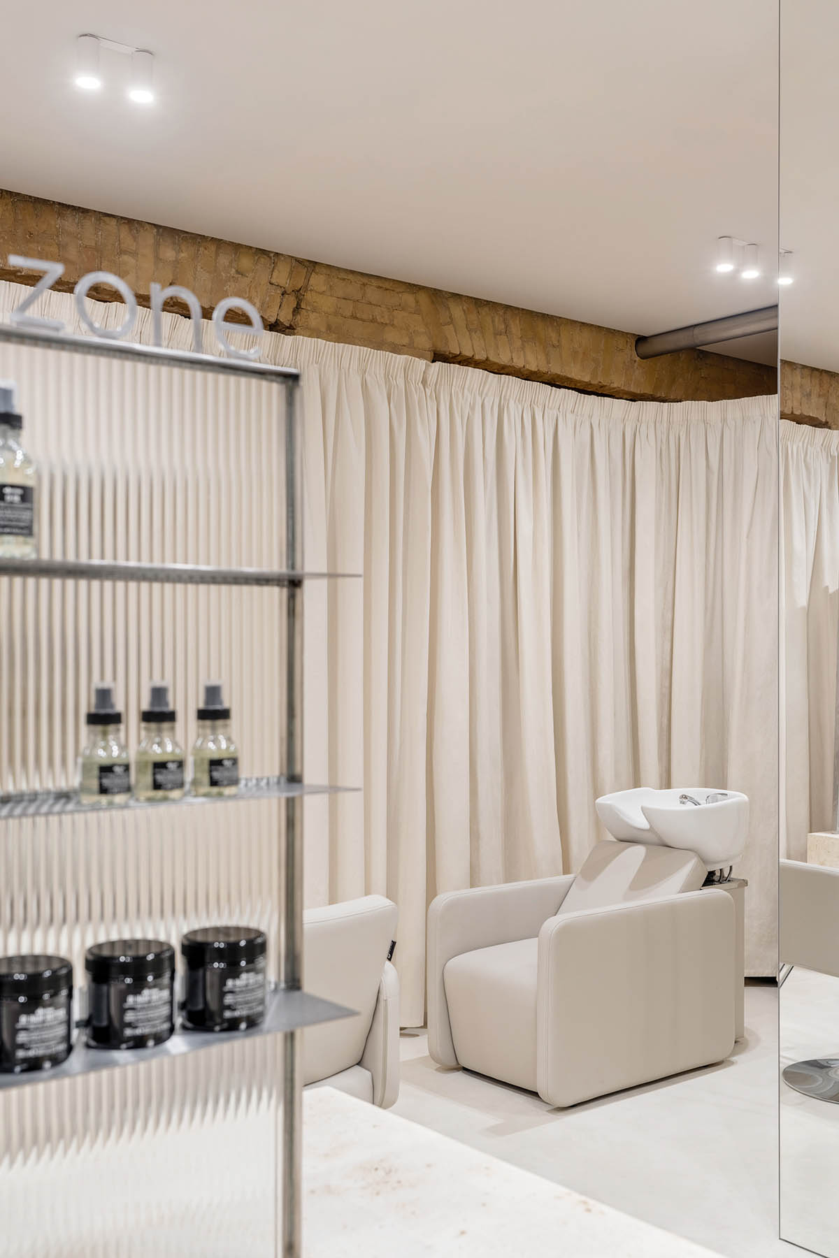 Tactile brick complements beige hues and mirrored surfaces for the interior of cosmetic showroom