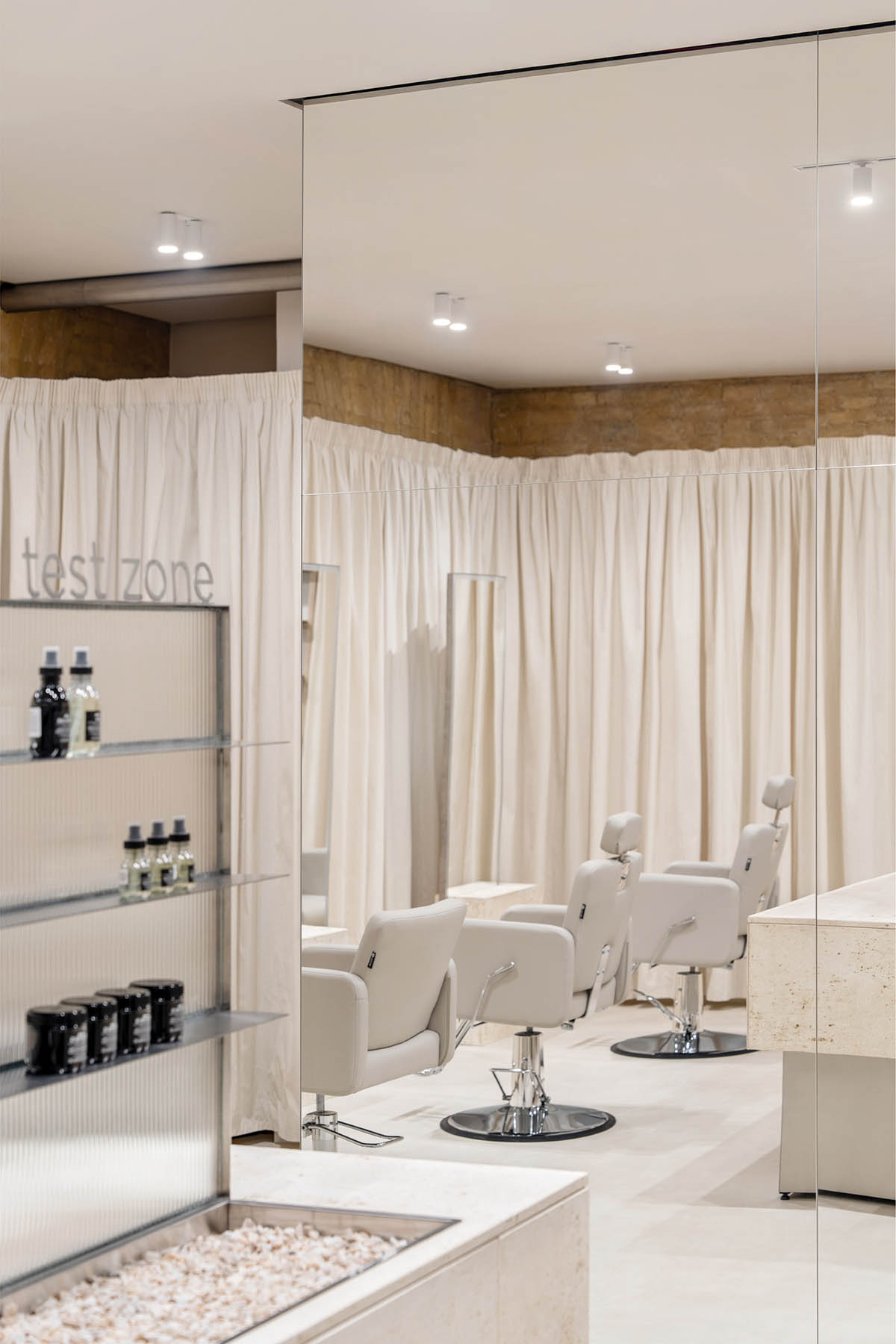Tactile brick complements beige hues and mirrored surfaces for the interior of cosmetic showroom
