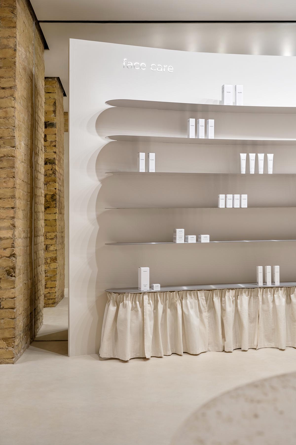 Tactile brick complements beige hues and mirrored surfaces for the interior of cosmetic showroom