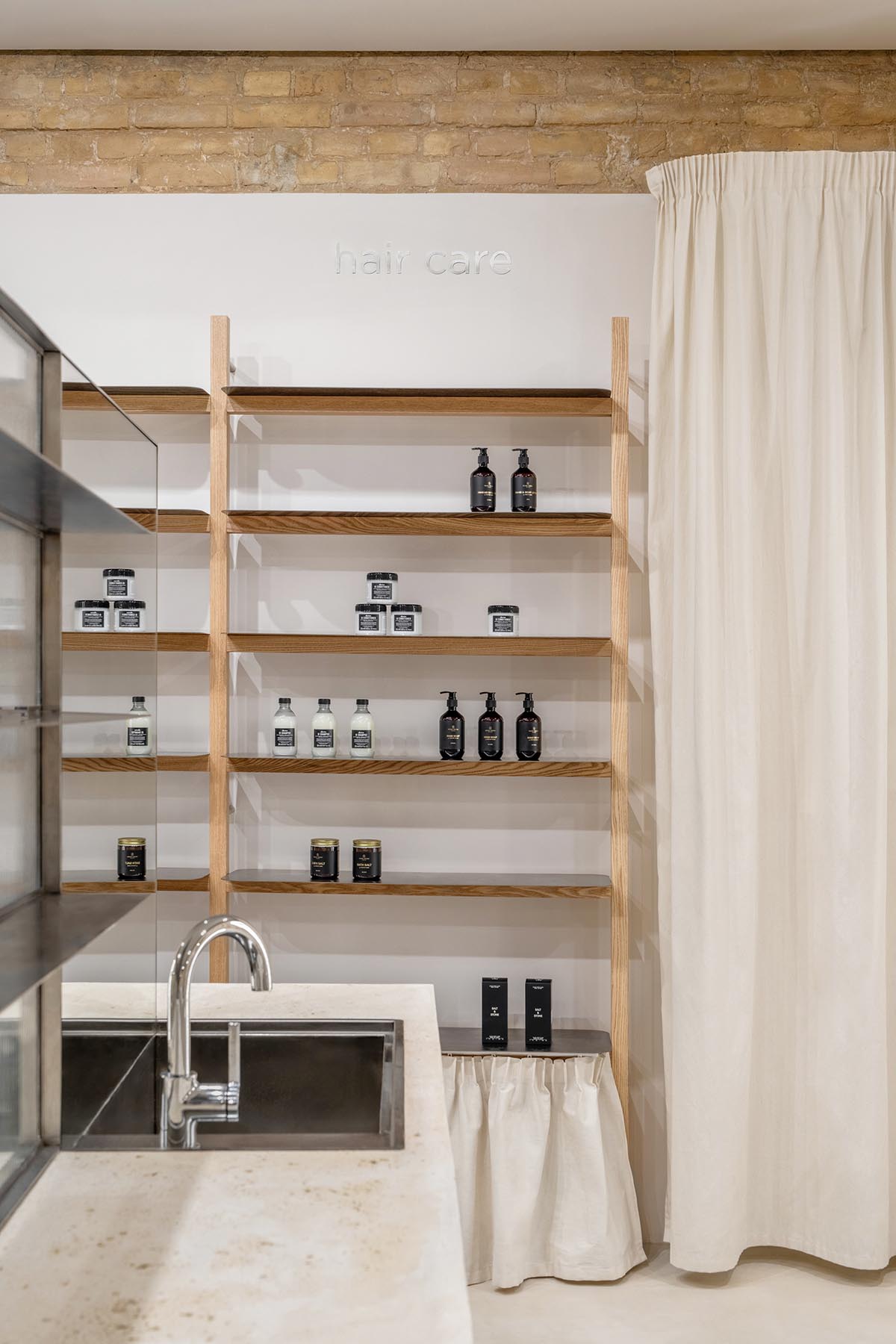 Tactile brick complements beige hues and mirrored surfaces for the interior of cosmetic showroom